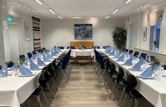 Bildet viser bord pyntet i et utleielokale. Bordene er pyntet til fest.