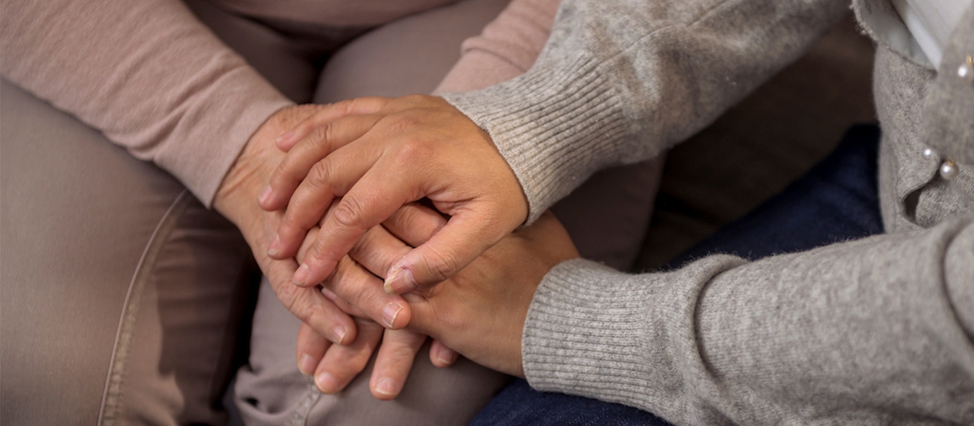 To personer sitter i en sofa og holder på hverandres hender