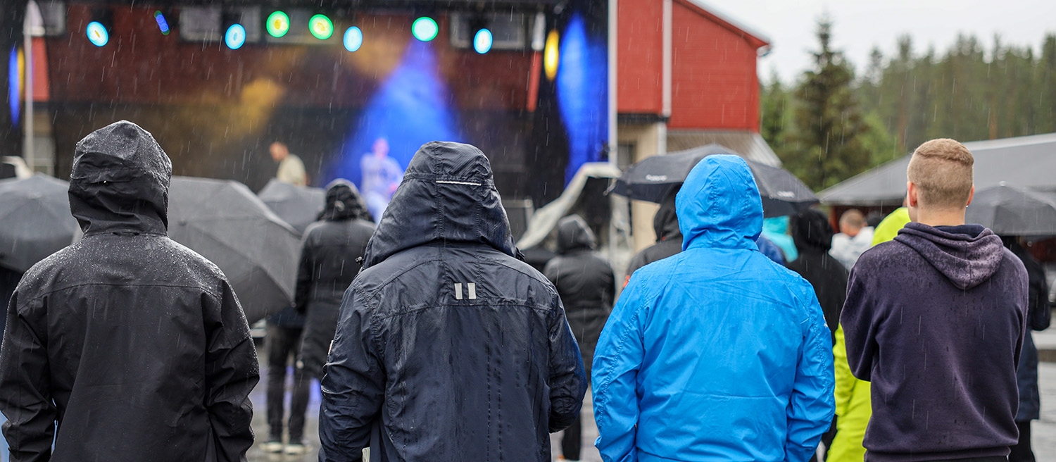 Fire innsatte står i regnværet foran scenen under fengselskonserten