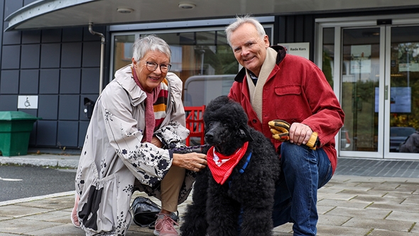 Ellen Skjølsvold fra Røde Kors og Svein fra Frimurerlogen sammen med besøkshunden Kaisa, foran inngangsdøra hos Røde Kors på Nardo i Trondheim