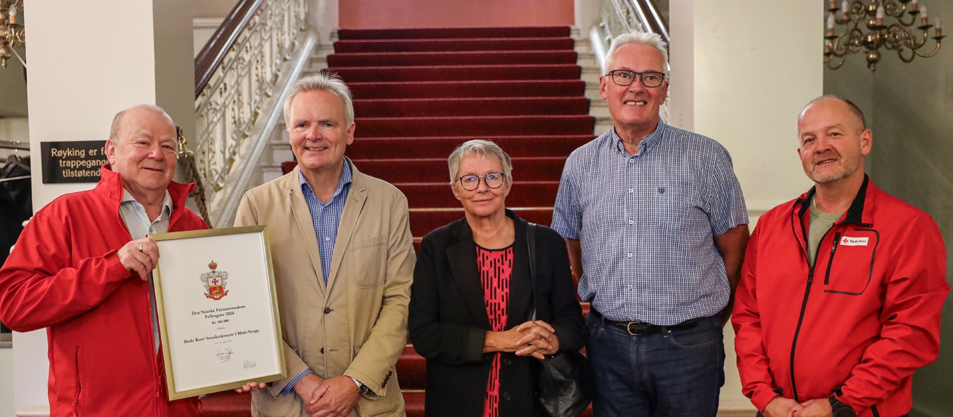 Tre representanter fra Røde Kors besøkte Frimurerlogen i Trondheim. Her står de sammen med to fra Frimurerlogen foran en trapp inne i Frimurerlogens lokaler i Trondheim