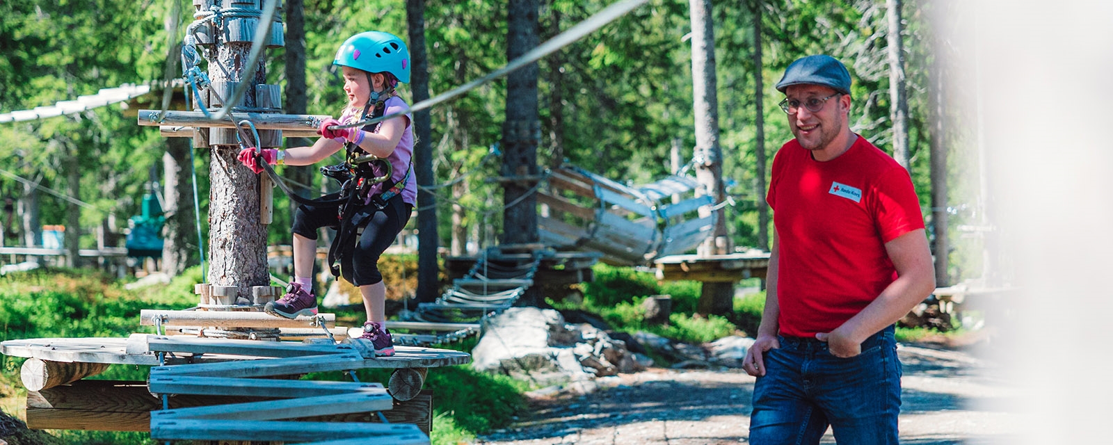 Frivillig følger barn gjennom klatreløype.