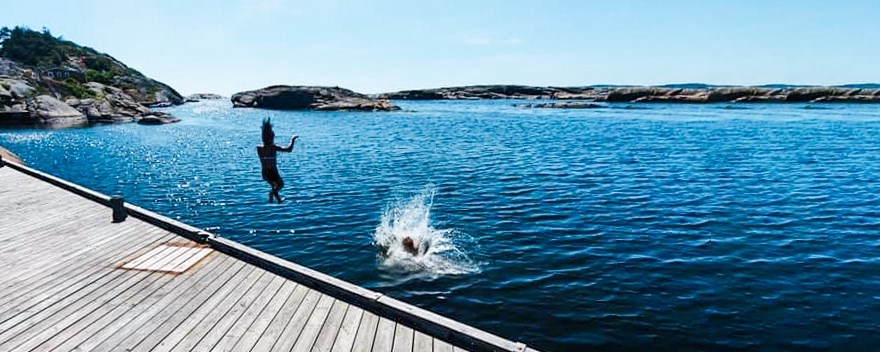 Ungdom bader fra bryggekant en sommerdag.