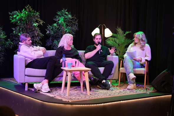 Fire personer sitter på en scene og prater sammen