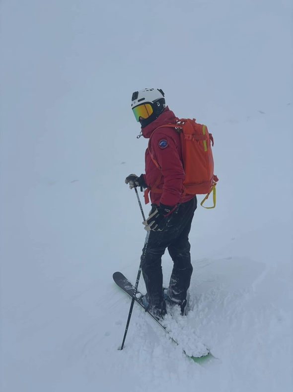 Mann står i full påkledning ute i snøen. Det er mye tåke.