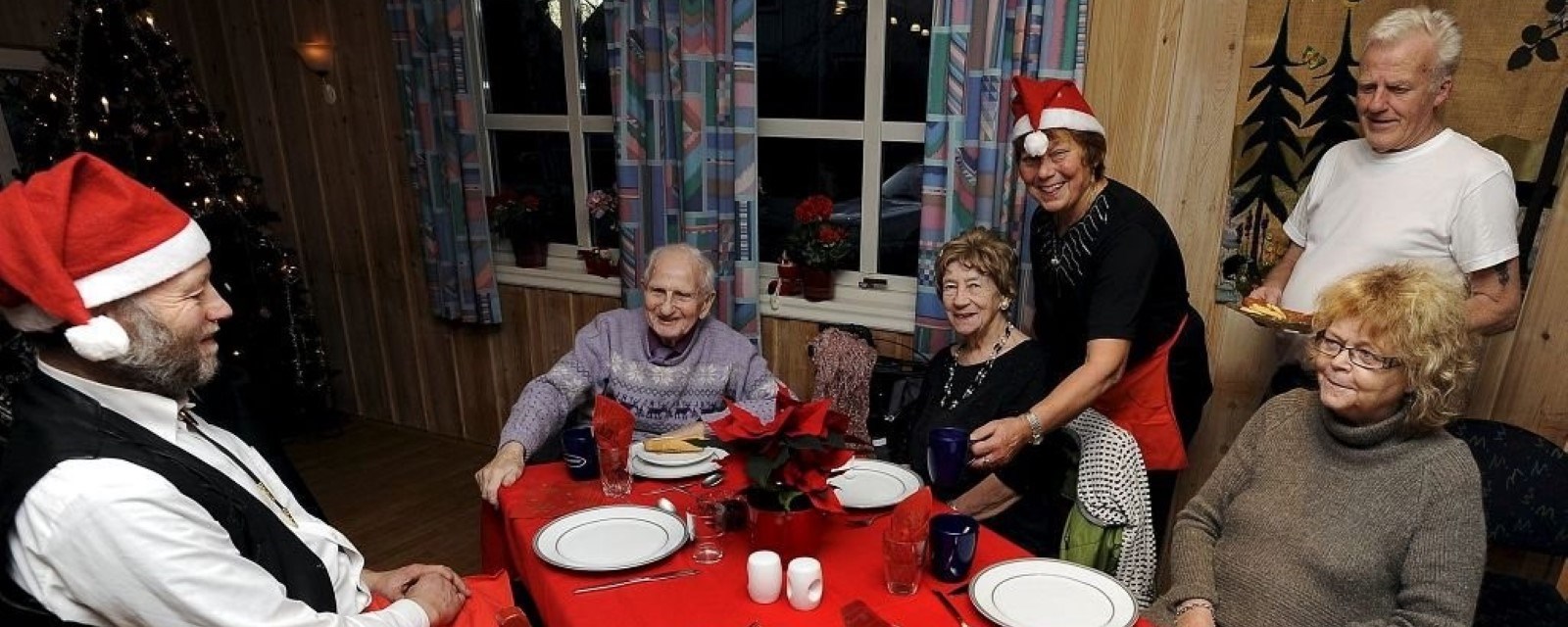 Et lag med voksne og eldre sitter rundt et bord dekket for julekos