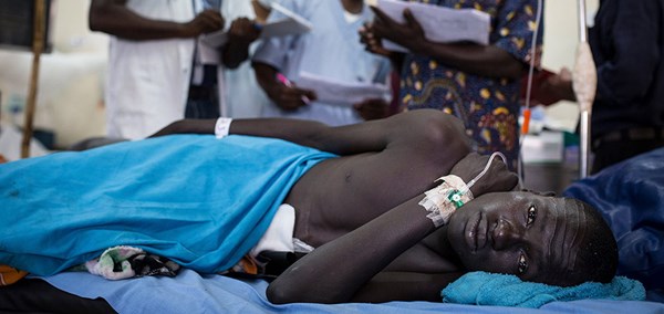 Man laying wounded on a hospital bed, indorrs, South Sudan