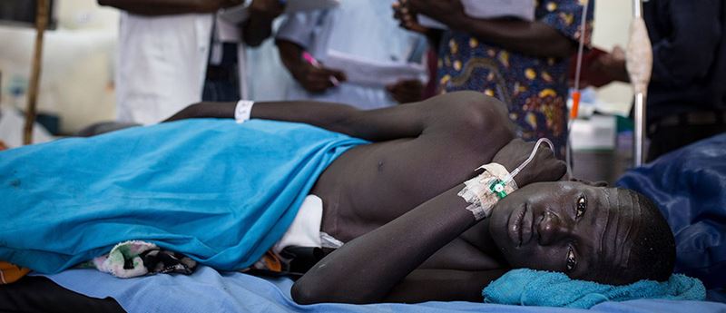 Man laying wounded on a hospital bed, indorrs, South Sudan