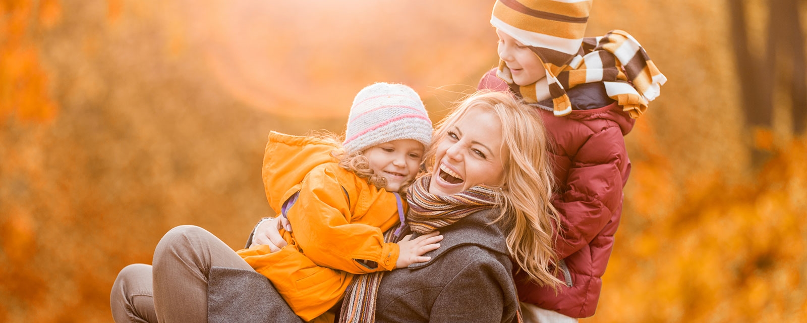 Kvinne leker med to barn og ler hjertelig