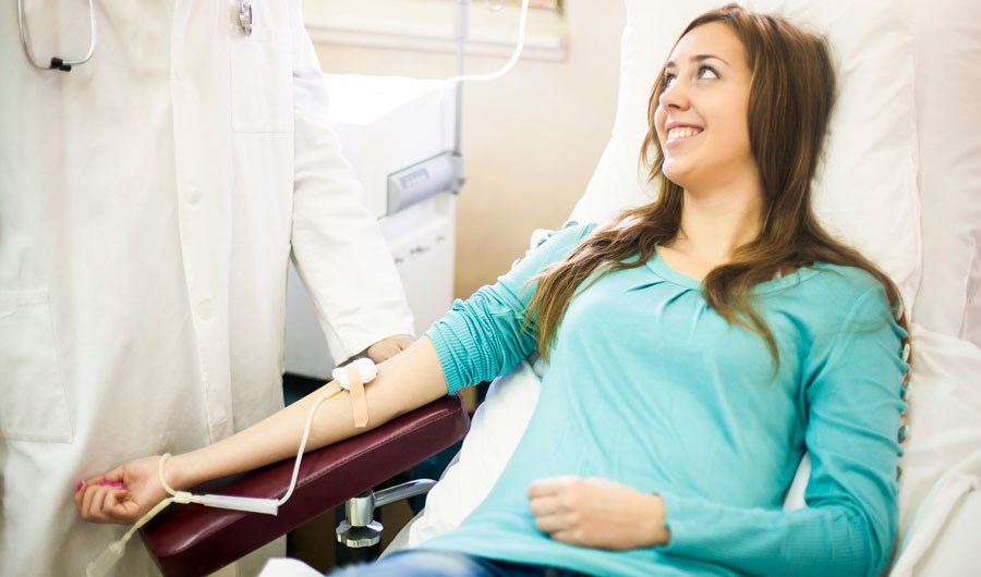 Kvinnelig blodgiver sitter i blodgiverstol med armen klar