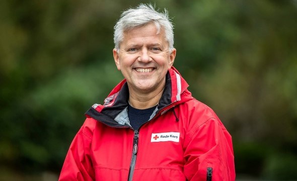 Mann i rød jakke smiler til kamera