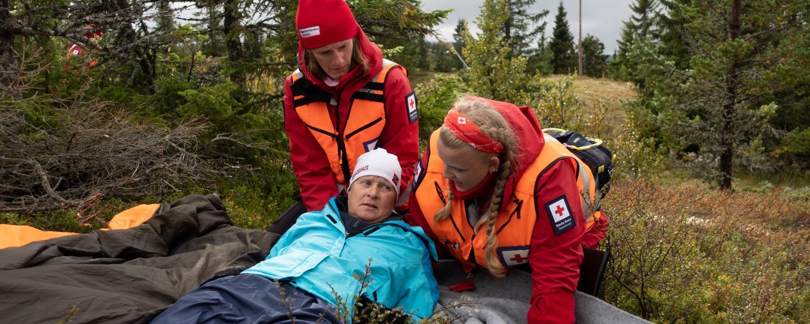 To damer i hjelpekorpset hjelper turgåer i skogen.