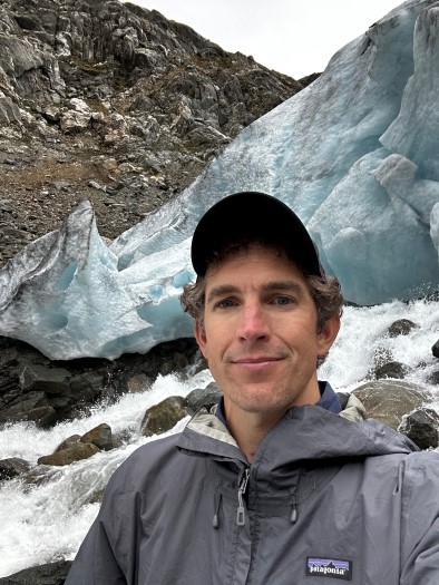 En mann står foran en isbre med turklær.