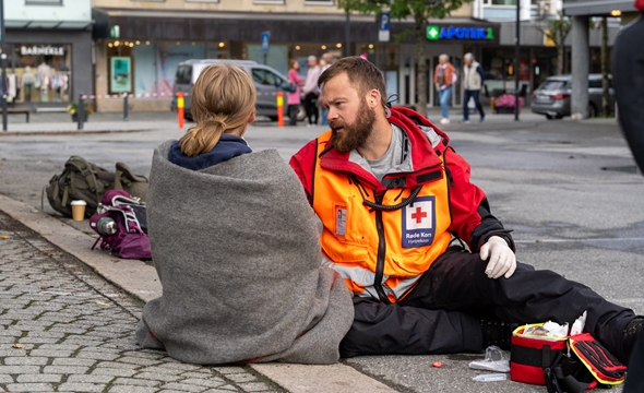 en kvinne får hjelp av en mann i hjelpekorpsuniform