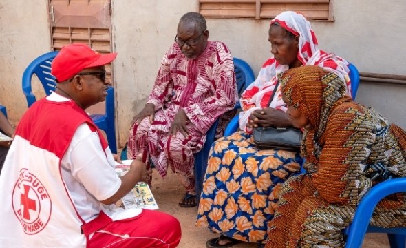En mann sitter foran tre personer og forteller noe viktig.