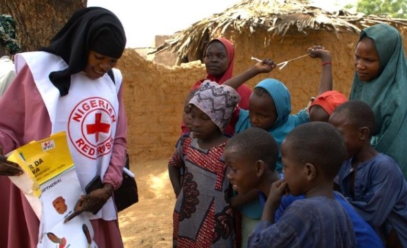 En kvinne viser en plakat med helseinformasjon til en gruppe mennesker.