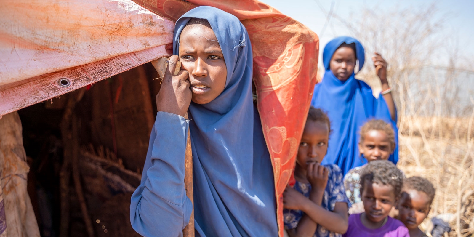 Jente med søsken utenfor hytte