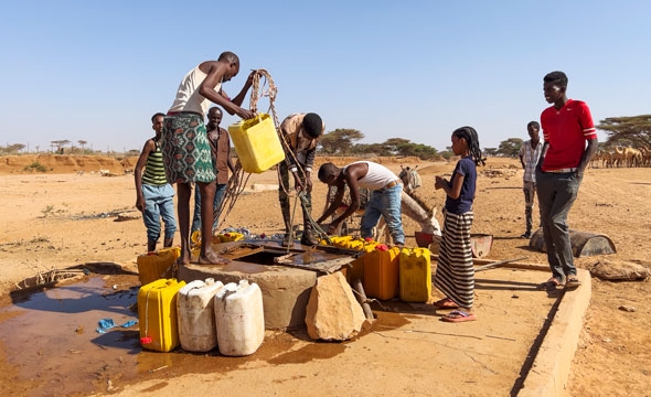 Folk henter vann i brønn
