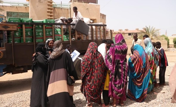 En gruppe mennesker står ved en lastebil som deler ut nødhjelp i Sudan.