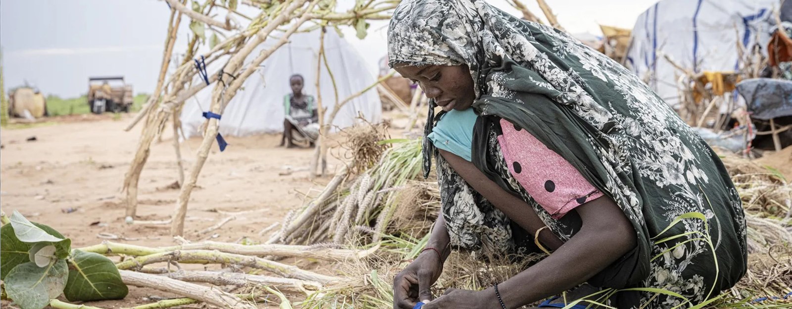 Mor dame sitter ute og binder greiner