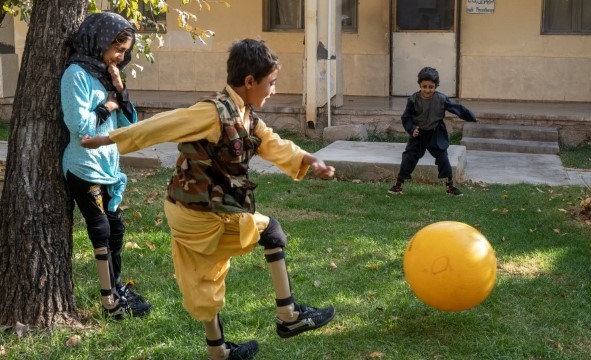 Tre søsken leker utenfor en ortopedisk klinikk. De trenger skinner for å gå og har kommet for oppfølging.