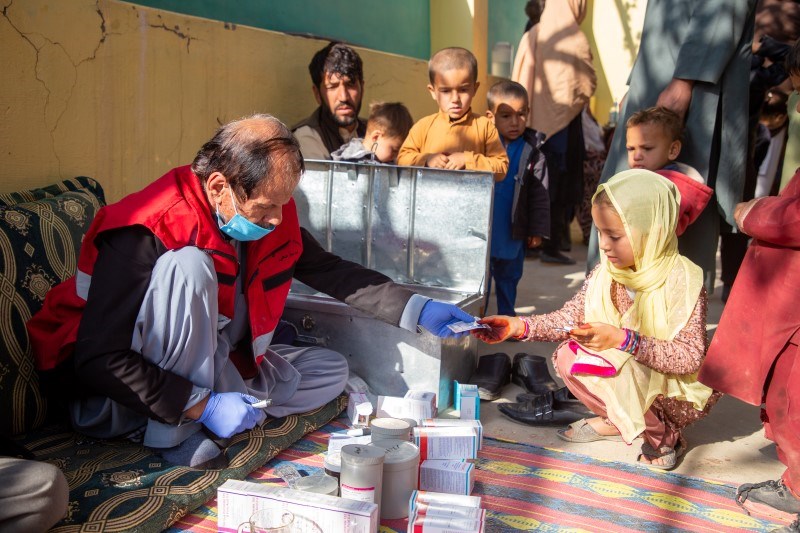 En mann fra Afghanistan Røde Halvmåne gir medisiner til en ung jente