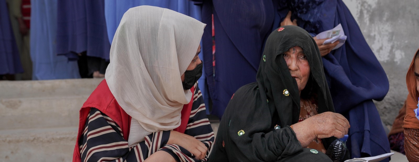 En kvinne fra Afghansk Røde Halvmåne snakker med en eldre kvinne.