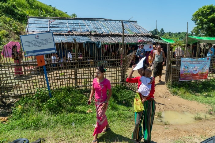 To kvinner og en baby står utenfor en helseklinikk som drives av Røde Kors.