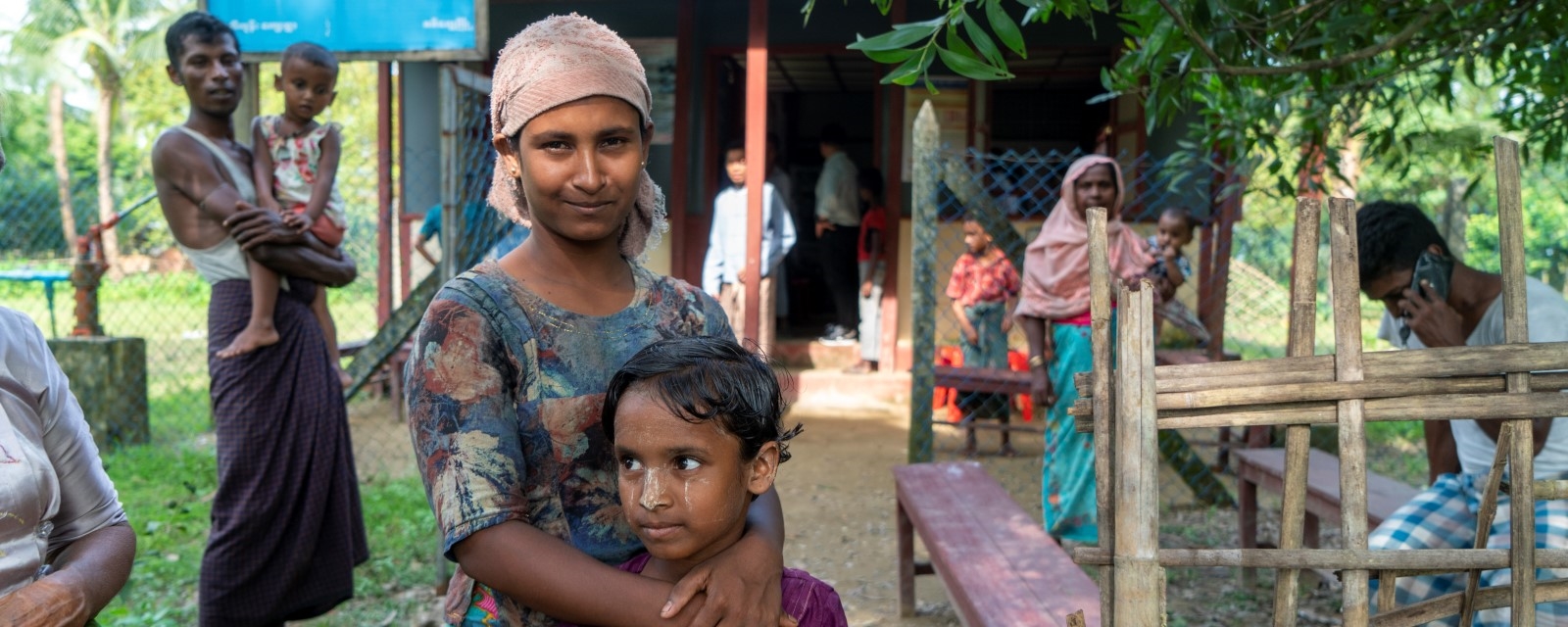 En kvinne besøker en helseklinikk og holder hendene beskyttende rundt datteren sin.