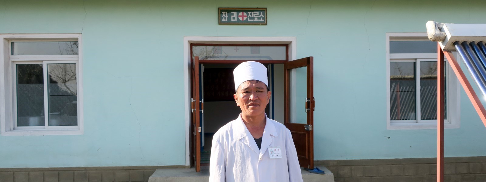 En mannlig lege står foran en Røde Kors-klinikk