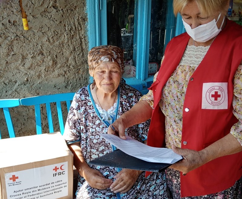 Røde Kors-frivillig deler ut nødhjelp til eldre kvinne.