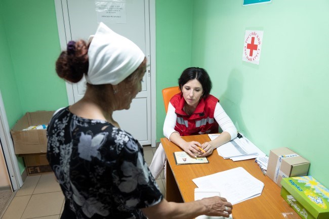 En kvinne fra Røde Kors snakker med en dame på et kontor