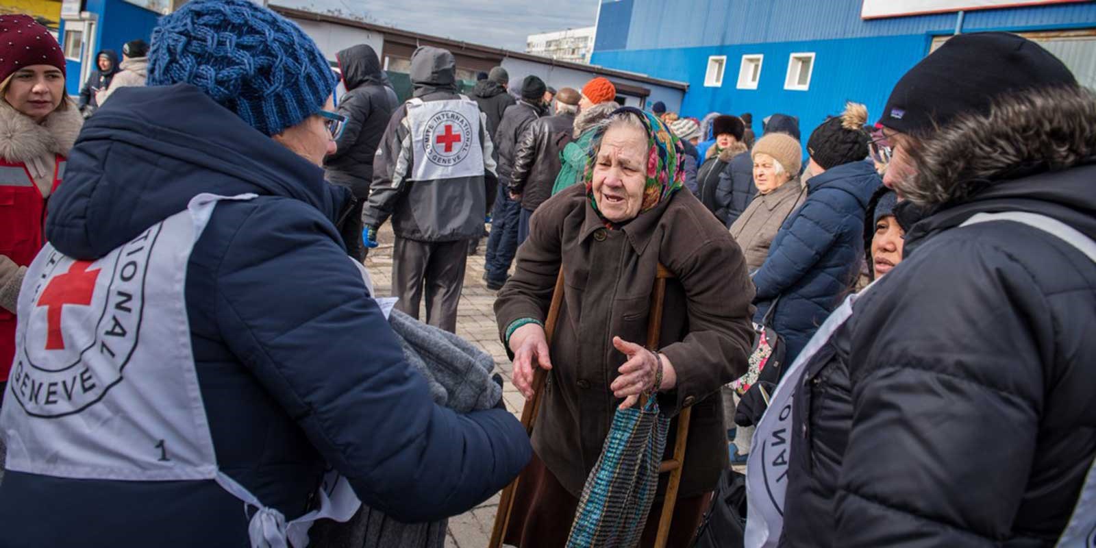 En eldre kvinne mottar ulltepper fra røde kors frivillige
