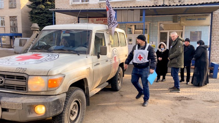 Personer fra Røde Kors står ved en Røde Kors-bil