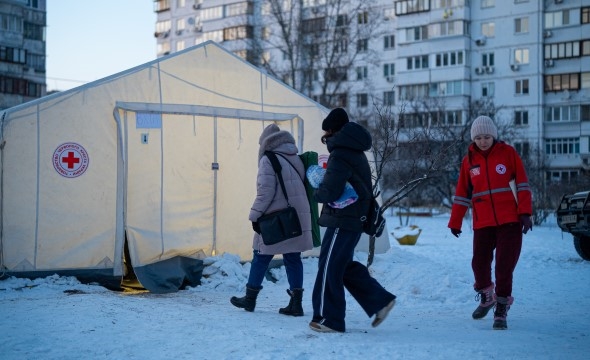 To personer besøker et varmetelt som er satt opp av Røde Kors.