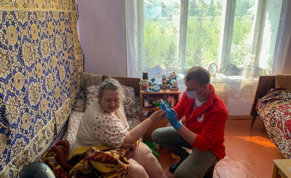 en eldre kvinne får medisinsk behandling av Røde Kors helsepersonell