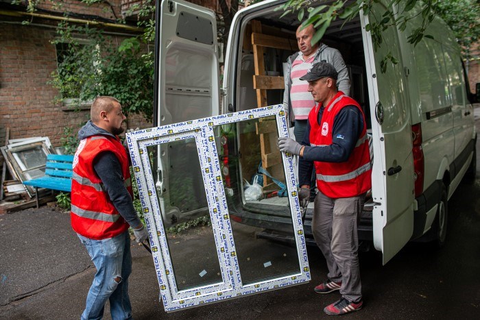 To menn fra Røde Kors Ukraina bærer inn et nytt vindu.