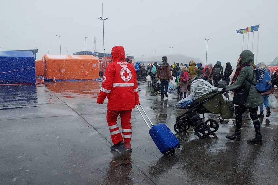 En frivillig fra rumensk røde kors hjelper flyktninger på flyplass, sludd og snø