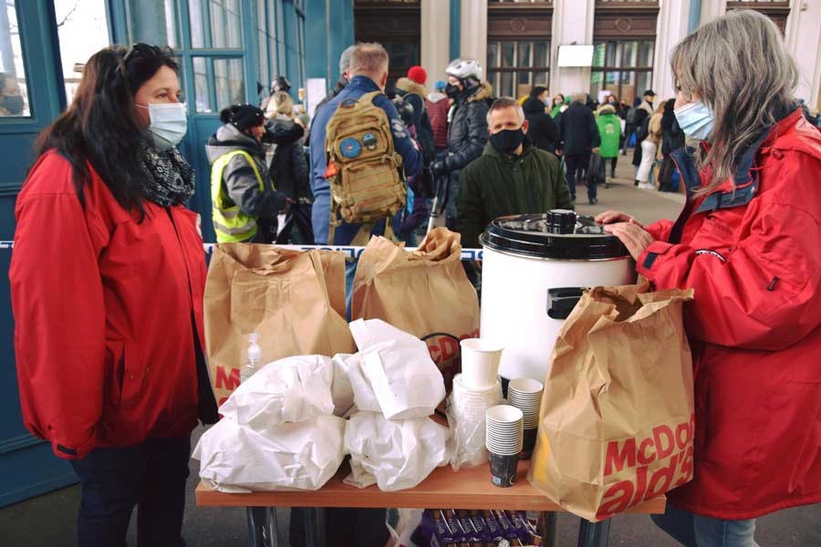 2 kvinner fra ungarn røde kors deler ut mat og drikke til ukrainske flyktninger