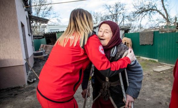 En kvinne fra Røde Kors klemmer en eldre kvinne