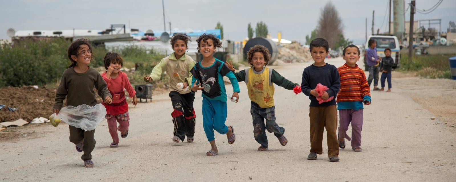 Flere barn løper sammen og leker i en flyktningleir i Libanon.