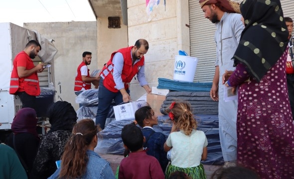 En gruppe mennesker står og venter på nødhjelp som frivillige fra Røde Kors deler ut.