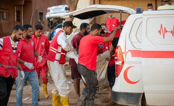 Frivillige fra Libya Røde Kors bistår på bakken etter ekstamvær og flom og løfter en skadet person inn i en ambulanse.