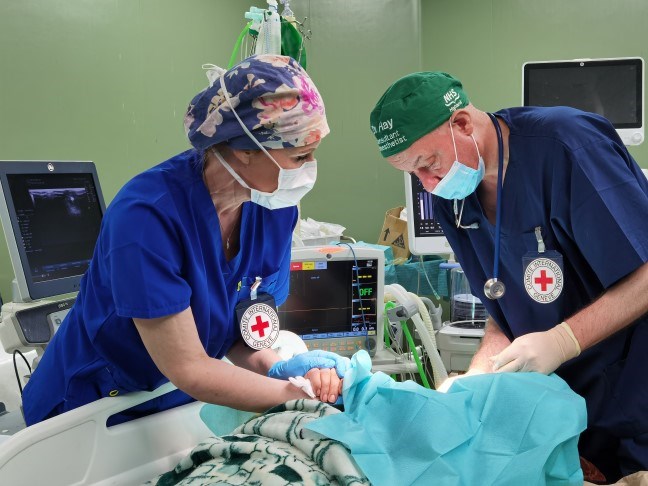 En kvinne og en mann står over en pasient som ligger på operasjonsbordet.