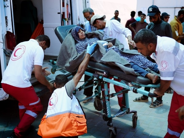 Frivillige i Palestinsk Røde Halvmåne triller en skadet kvinne inn i en ventende ambulanse.