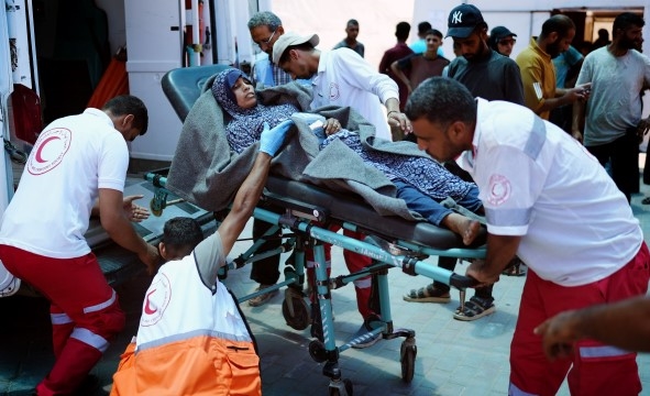 Frivillige i Palestinsk Røde Halvmåne triller en skadet kvinne inn i en ventende ambulanse.