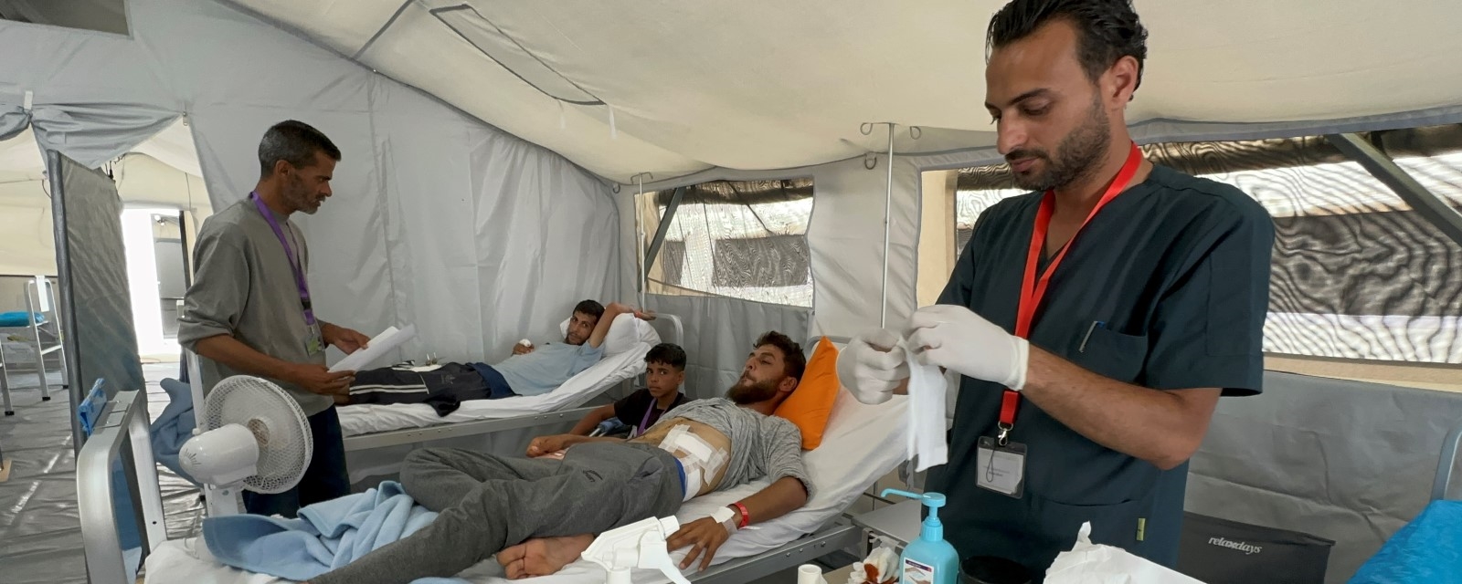 To menn ligger på feltsykehuset og får behandling av to helsearbeidere.