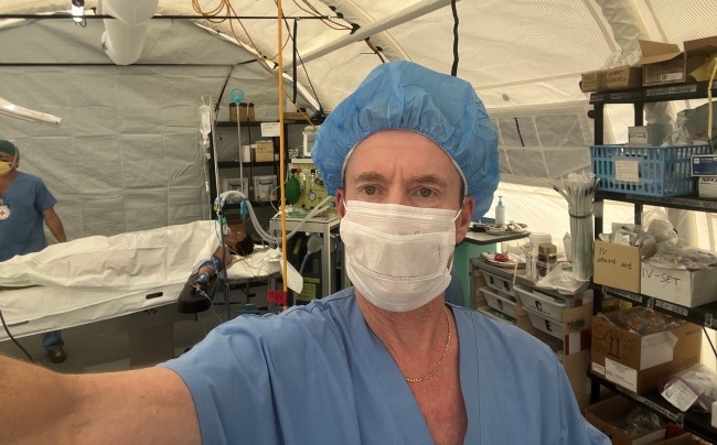 En mann med munnbind står foran en pasien på operasjonsbordet