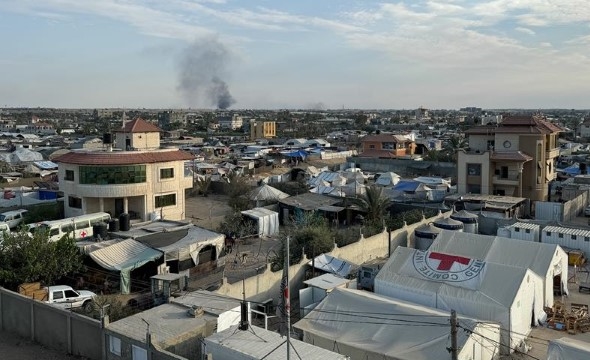 Et oversiktsbilde fra luften som viser et feltsykehus  midt i en by. Det ryker  svar røyk fra et sted i bakgrunnen fra en eksplosjon.
