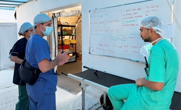 Tre kollegaer ved feltsykehuset snakker sammen.